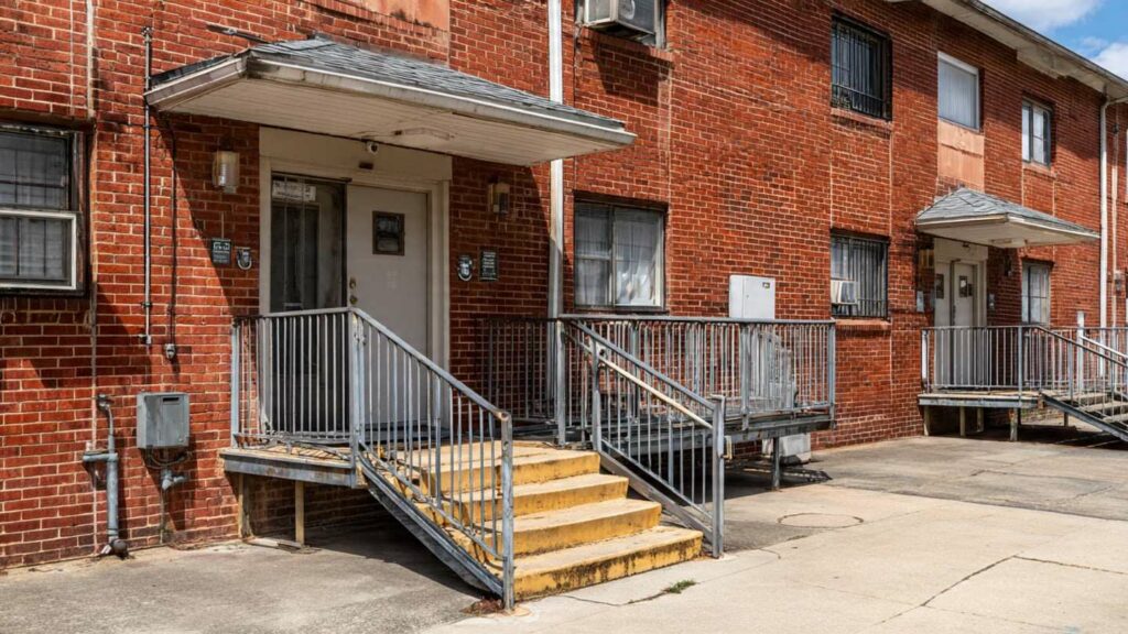 A modest apartment building with accessible features such as ramps and wide entrances, representing housing options for SSI recipients. 
